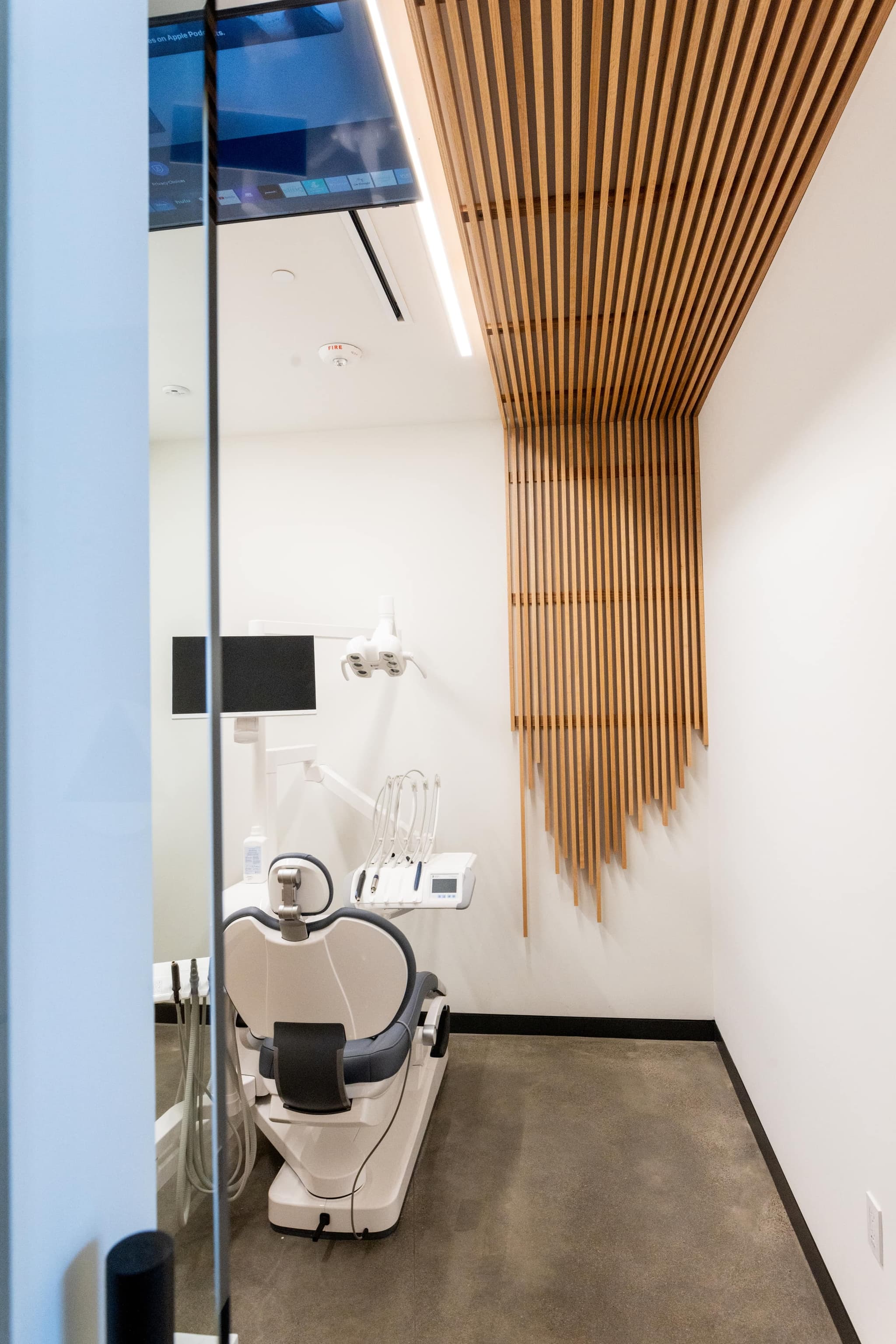 A treatment suite beneath a sculptural wood-slat ceiling detail