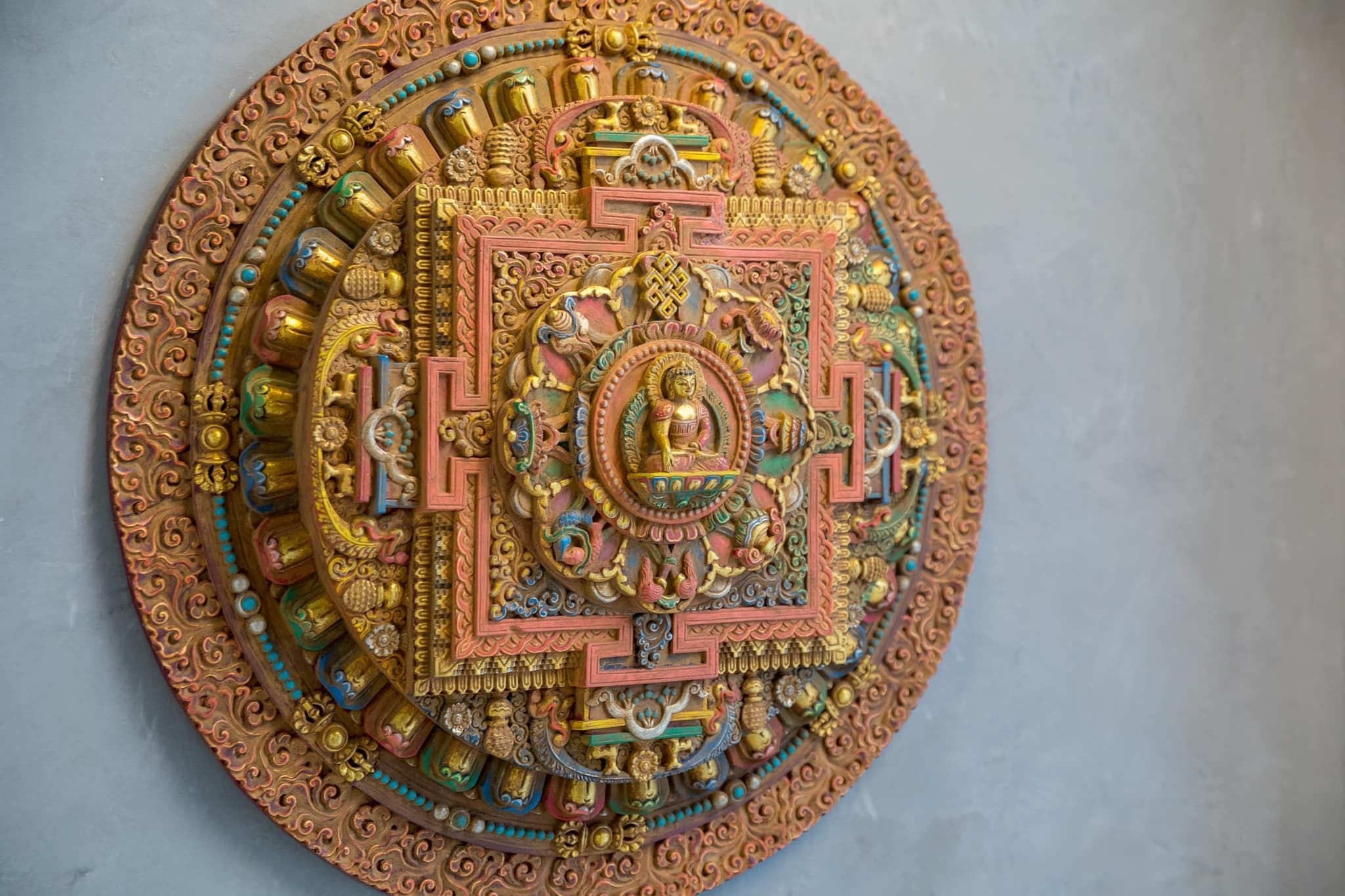 A hand-carved mandala mounted on a warm plaster wall