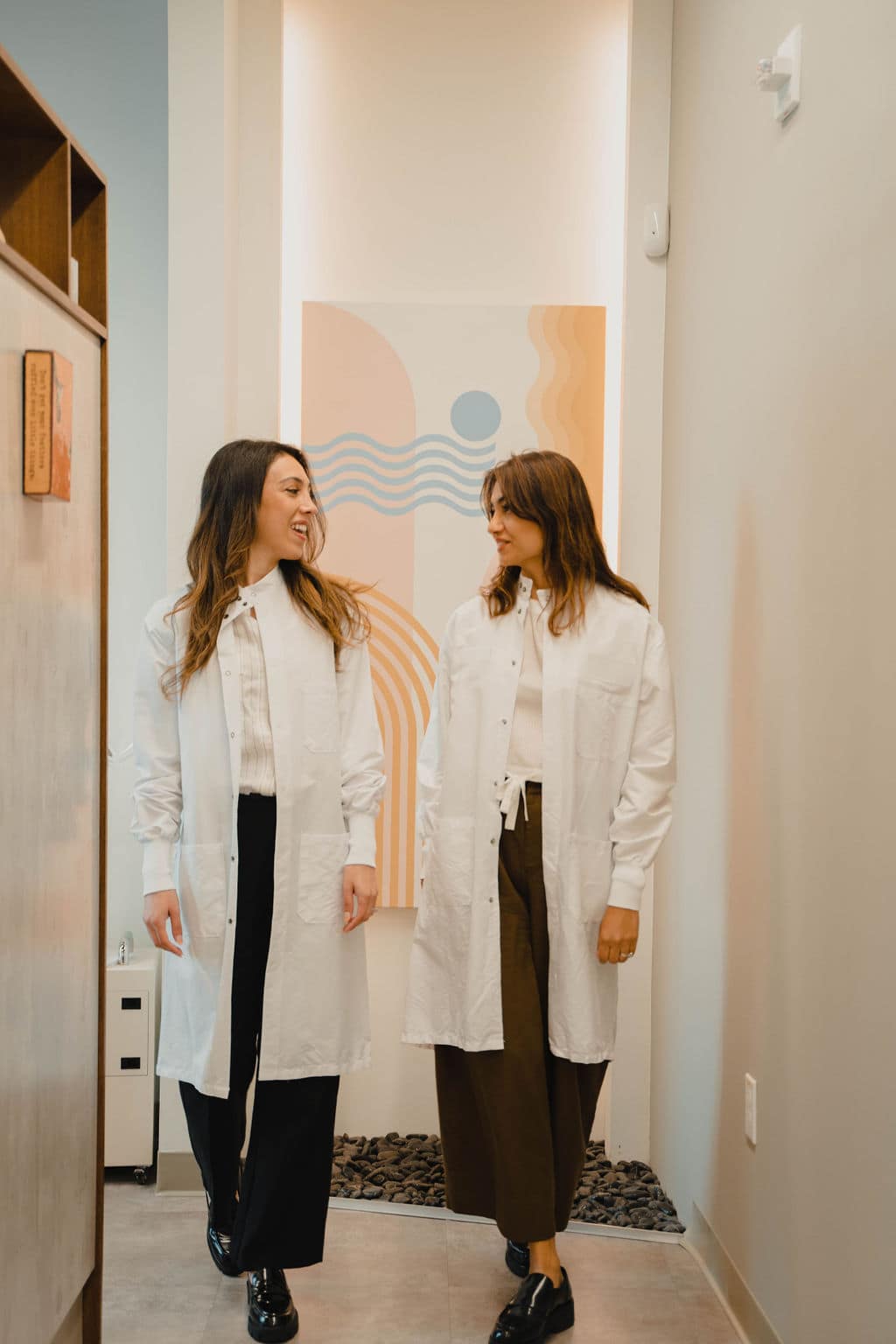 Two members of the Zen Dental Studio team talking in a bright corridor of the San Francisco studio